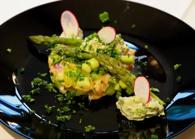 a black plate of food with asparagus and vegetables at Pax et Amor Chambres d'hôtes de charme - Charming B&B in Mazerolles-du-Razès
