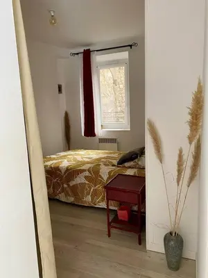 a bedroom with a bed and a window and a table at Accueillant petit T2 cœur de centre ville in Lézignan-Corbières
