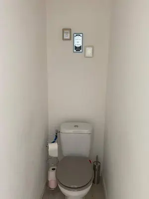 a bathroom with a toilet in a white wall at Accueillant petit T2 cœur de centre ville in Lézignan-Corbières