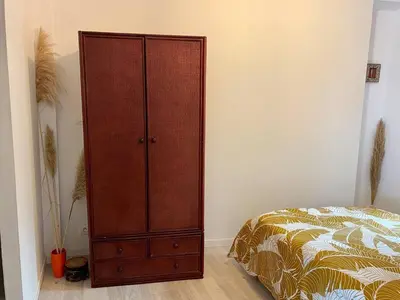 a bedroom with a wooden cabinet next to a bed at Accueillant petit T2 cœur de centre ville in Lézignan-Corbières