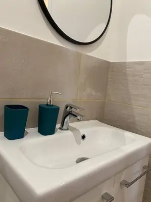 a bathroom sink with two cups and a mirror at Narbonne : Logement idéalement situé in Narbonne
