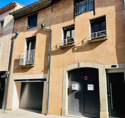 a building with two garage doors and two windows at Elegant and Charming Townhouse with roof terrace in Limoux