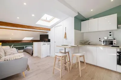 a kitchen with white cabinets and stools in a room at Charmant studio plein centre des couverts, calme et climatisé in Mirepoix