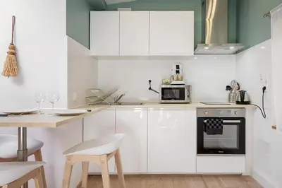 a kitchen with white cabinets and a table with chairs at Charmant studio plein centre des couverts, calme et climatisé in Mirepoix