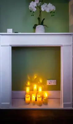 a fireplace with four yellow candles in it at Mas des 2 paons in Villedaigne