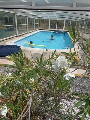 two people in a swimming pool in a building at Mas des 2 paons in Villedaigne
