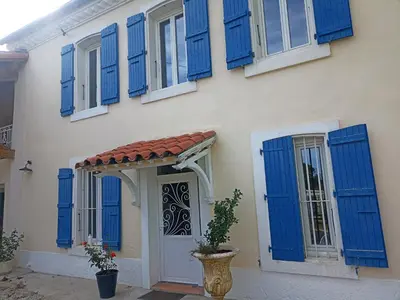 a house with blue shutters and a door at Mas des 2 paons in Villedaigne