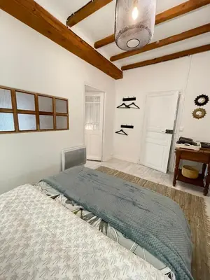 a bedroom with a bed and a table and a window at Maison Petit Arago avec roof terrace et parking privé in Carcassonne