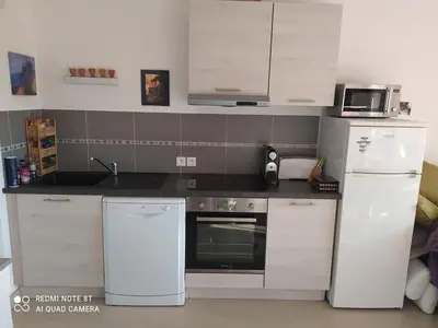 a kitchen with white appliances and a black counter top at Location saisonnière Résidence Ephyra Gruissan in Gruissan