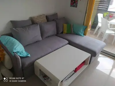 a living room with a gray couch and a table at Location saisonnière Résidence Ephyra Gruissan in Gruissan