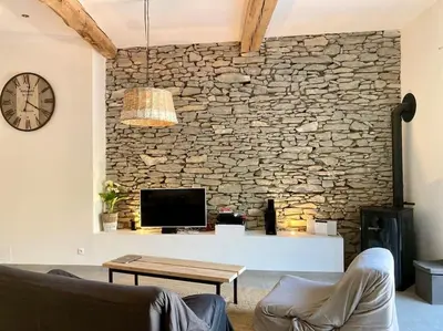 a living room with a stone wall and a tv at Piscine privée sans vis à vis / Calme / Babyfoot in Conques-sur-Orbiel