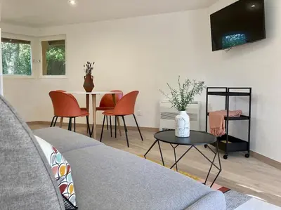 a living room with a couch and a table with chairs at Plein cœur de la nature ~ Jacuzzi Privé 24h/24h in Ventenac-Cabardès