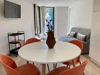 a living room with a white table and orange chairs at Plein cœur de la nature ~ Jacuzzi Privé 24h/24h in Ventenac-Cabardès