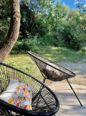 a chair with a pillow sitting next to a tree at Plein cœur de la nature ~ Jacuzzi Privé 24h/24h in Ventenac-Cabardès