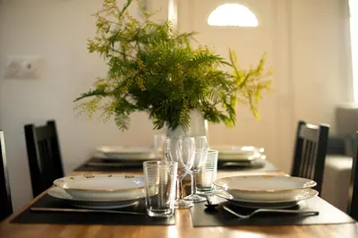 a dining room table with plates and glasses and a centerpiece at Charmant havre de paix à 10 mn de Carcassonne, mer, montagne et trésors de l'unesco à portée de main in Villemoustaussou