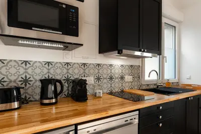 a kitchen with black cabinets and a wooden counter top at Charmant havre de paix à 10 mn de Carcassonne, mer, montagne et trésors de l'unesco à portée de main in Villemoustaussou