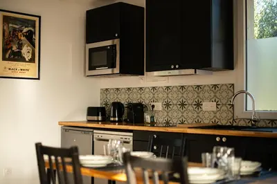 a kitchen with a table with chairs and a microwave at Charmant havre de paix à 10 mn de Carcassonne, mer, montagne et trésors de l'unesco à portée de main in Villemoustaussou