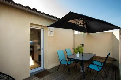 a table and chairs with an umbrella on a deck at Charmant havre de paix à 10 mn de Carcassonne, mer, montagne et trésors de l'unesco à portée de main in Villemoustaussou