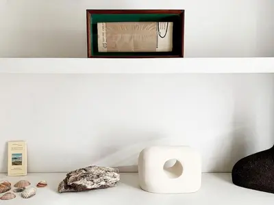 a shelf with a clock and a roll of toilet paper and a rock at La Grande Traverse gîte d'exception de bord de mer in Lapalme