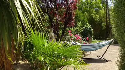 a hammock in a garden with a statue and flowers at Ty Calon Lan in Montazels