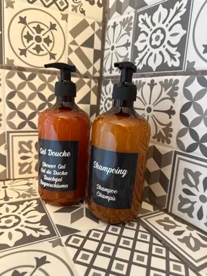 two bottles of soap sitting on a tiled floor at Le carré Gambetta in Carcassonne