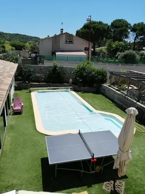 a swimming pool with a table and an umbrella at Gîte et Chambre d'hôte Entre Tilleul et Agrumes in Vinassan