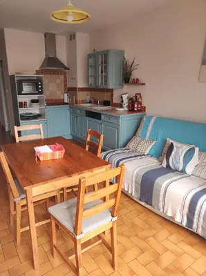 a kitchen with a wooden table and a couch and a table and a table at Chez Armelle in Port-la-Nouvelle