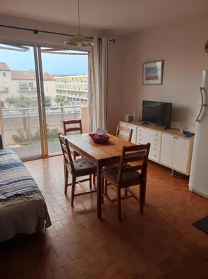 a dining room with a table and chairs and a television at Chez Armelle in Port-la-Nouvelle