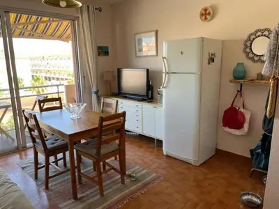 a dining room with a table and a refrigerator at Chez Armelle in Port-la-Nouvelle