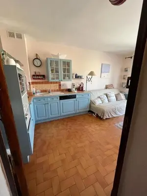 a kitchen with blue cabinets and a living room at Chez Armelle in Port-la-Nouvelle