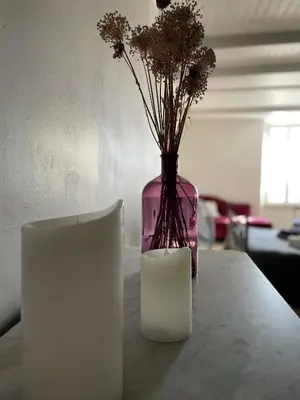 a vase with flowers and a candle on a table at Le Taurillou in Taurize