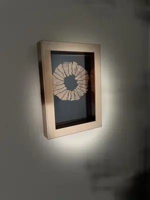 a light on a wall with a picture on it at Le Taurillou in Taurize