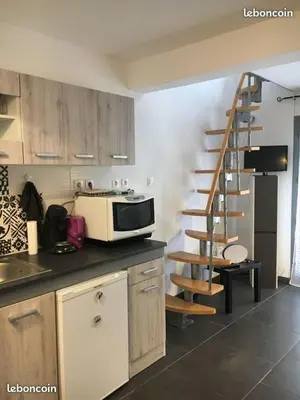 a kitchen with a microwave on a counter and a staircase at Escale à Castelnaudary in Castelnaudary