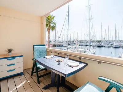 a table and chairs on a balcony with a marina at Studio cabine avec piscine et vue port à Gruissan - FR-1-409-199 in Gruissan