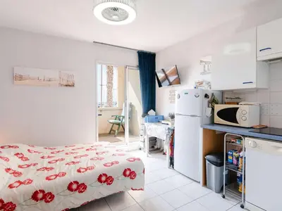 a bedroom with a bed and a kitchen with a refrigerator at Studio cabine avec piscine et vue port à Gruissan - FR-1-409-199 in Gruissan