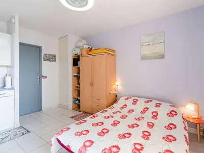 a bedroom with a bed with red flowers on the bedspread at Studio cabine avec piscine et vue port à Gruissan - FR-1-409-199 in Gruissan
