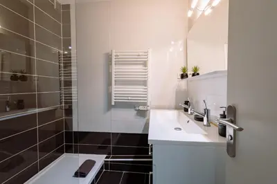 a white bathroom with a sink and a shower at L'Évêché - T3 Spacieux & Traversant en Hypercentre in Castres