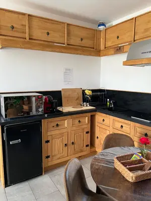 a kitchen with wooden cabinets and a black refrigerator at Le CLOS du LÉZARD - L'escapade in Port-la-Nouvelle