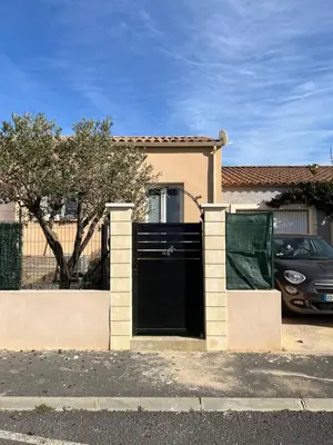 a house with a black gate and a car parked at Le CLOS du LÉZARD - L'escapade in Port-la-Nouvelle