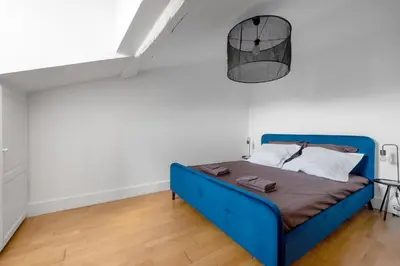 a blue bed in a room with white walls at Charmand duplex avec vue sur la cité & les toits in Carcassonne
