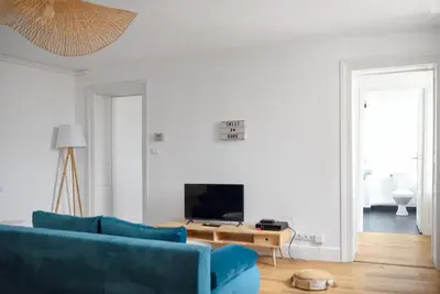 a living room with a blue couch and a tv at Charmand duplex avec vue sur la cité & les toits in Carcassonne