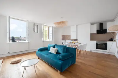 a living room with a blue couch and a kitchen at Charmand duplex avec vue sur la cité & les toits in Carcassonne