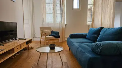 a living room with a blue couch and a table at Charmand duplex avec vue sur la cité & les toits in Carcassonne