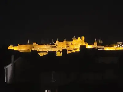 a view of a city at night with lights at Charmand duplex avec vue sur la cité & les toits in Carcassonne