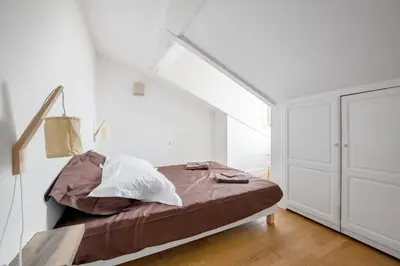 a bedroom with a bed and a white wall at Charmand duplex avec vue sur la cité & les toits in Carcassonne