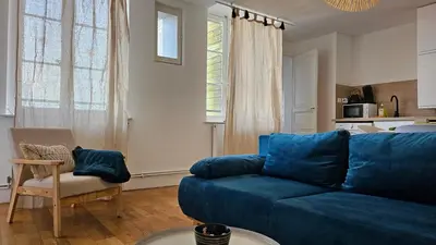a living room with a blue couch and a chair at Charmand duplex avec vue sur la cité & les toits in Carcassonne