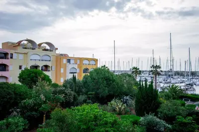 a building in front of a marina with boats at Logis des Goélands YourHostHelper in Gruissan