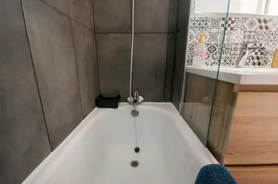 a bath tub in a bathroom next to a sink at Logis des Goélands YourHostHelper in Gruissan