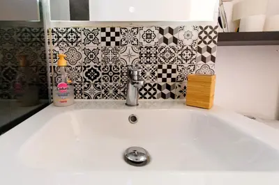 a white sink in a bathroom with black and white tiles at Logis des Goélands YourHostHelper in Gruissan