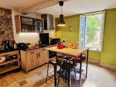 a kitchen with green walls and a table with chairs at L'Orée de la cité in Carcassonne